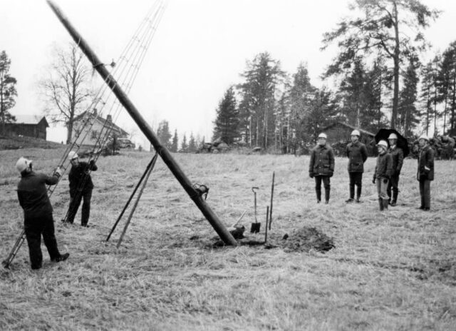 Kuvassa käytetään metallisia tukirakenteita vaijerin kiinnityspisteenä pylvään nostossa.